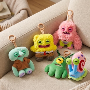 May include: Five plush keyrings featuring cartoon characters. The characters include a yellow square with a tie, a pink furry creature, a green squid-like figure, a green one-eyed creature, and a snail. Each keyring has a gold-coloured ring.