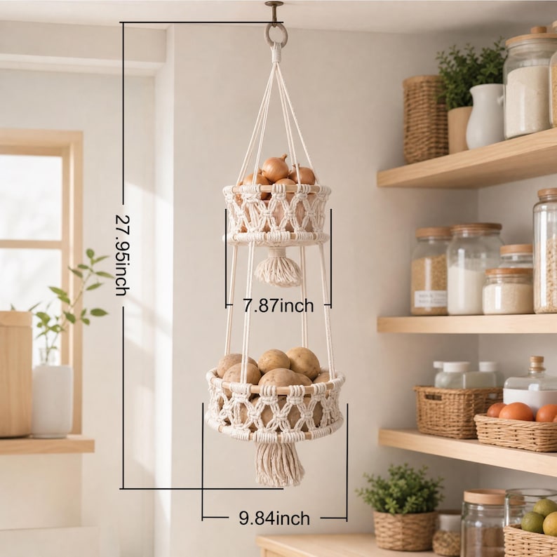 May include: A two-tiered, macrame hanging basket, 27.95 inches in height, filled with onions and potatoes. The baskets are 7.87 inches and 9.84 inches in diameter, respectively. The off-white macrame design adds a rustic touch to the kitchen.