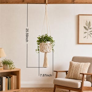 May include: A macrame plant hanger with a white ceramic pot filled with green plants. The hanger is suspended from a wooden beam. The overall height is 25.59 inches, and the width is 7.87 inches.