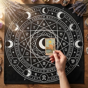 May include: A black tarot cloth with a white celestial design featuring moons, stars, and symbols. A hand holds a tarot card labeled "THE STAR." The scene includes lavender, crystals, and other mystical items, creating a spiritual aesthetic.