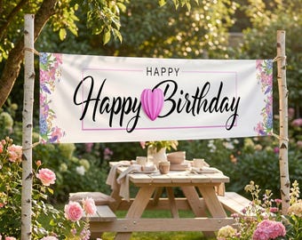 Könnte beinhalten: Ein weißes Banner mit dem Schriftzug "Happy Birthday" in eleganter Schrift und einem rosa Herz. Das Banner ist mit floralen Mustern verziert und wird im Freien über einem Picknicktisch präsentiert.
