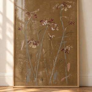 May include: A framed vertical wall art print featuring an abstract floral illustration on a solid brown background. The artwork displays stylised flowers with thin, light grey stems and dark red petals, accented by subtle white and pink brushstrokes.