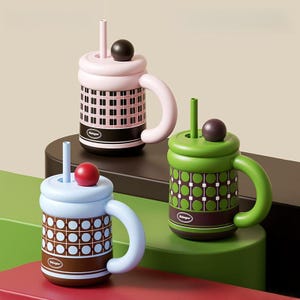 May include: Three cylindrical mugs with lids, straws, and rounded handles. The top mug is pink with a black grid pattern. The bottom left mug is light blue with a brown grid pattern. The bottom right mug is green with a dark green circle pattern.