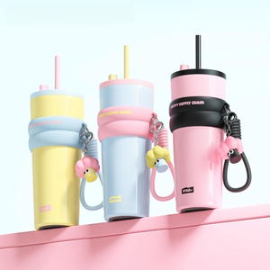 May include: Three colorful insulated tumblers with straws and sheep-shaped keychains. The tumblers are yellow, light blue, and pink, each with a matching colored lid and straw. The text "HAPPY SUPPLY CHAIN" is printed on the pink and light blue tumblers.