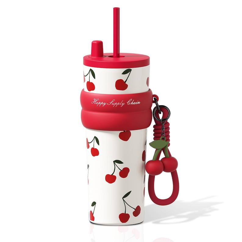 May include: A white tumbler with a red cherry pattern, a red lid, and a matching red straw. A red silicone band features the text Happy Supply Chain. A red cherry charm hangs from a black ring attached to the side of the silicone band.
