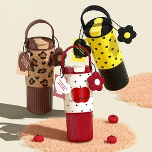 May include: Three insulated water bottles with handles and decorative charms. One has a leopard print, another has black hearts on yellow, and the third has an apple design with the text "Happy Valentine's Day". Each bottle has a tag.
