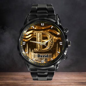 K&ouml;nnte beinhalten: Schwarze Armbanduhr mit goldenem Zifferblatt mit dem Buchstaben "D" und dem Namen "David". Die Uhr hat ein schwarzes Armband und eine goldfarbene L&uuml;nette mit Zahlen. Das Zifferblatt hat ein Landschaftsdesign.
