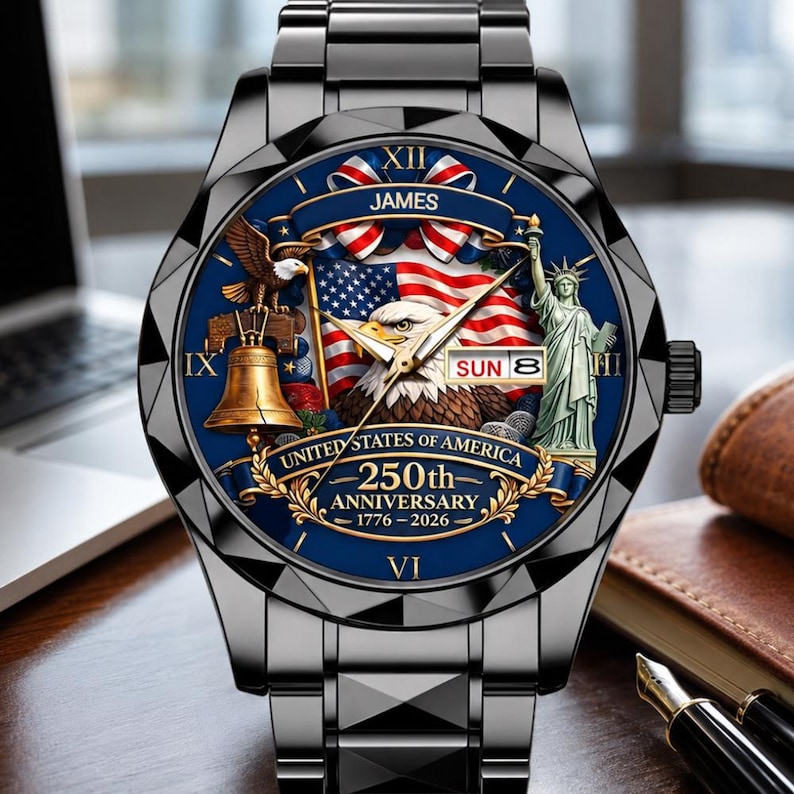 May include: A black metal wristwatch with a blue dial featuring a bald eagle, the Statue of Liberty, the Liberty Bell, and an American flag. The dial includes the text JAMES, UNITED STATES OF AMERICA, 250th ANNIVERSARY, 1776-2026, and SUN 8.