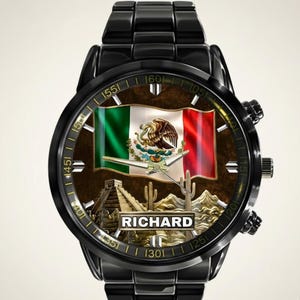 May include: Black wristwatch featuring the Mexican flag on the watch face, with the name "RICHARD" below. The watch face also includes images of a pyramid, cacti, and mountains. The watch has a black metal band.