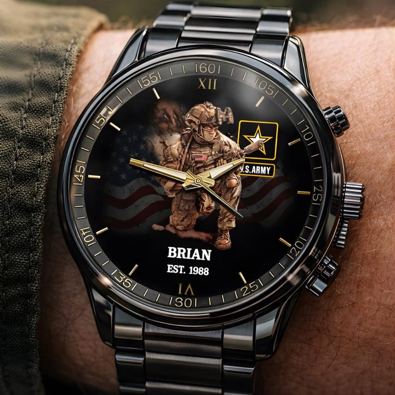 Puede incluir: Reloj de pulsera negro con correa y esfera negras. La esfera del reloj presenta un gr&aacute;fico de un soldado, la bandera estadounidense y el texto "BRIAN EST. 1988". El reloj tiene manecillas y marcadores dorados, y el logotipo del ej&eacute;rcito estadounidense.