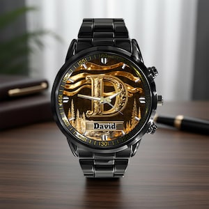 K&ouml;nnte beinhalten: Eine schwarze Armbanduhr mit einem goldfarbenen Zifferblatt mit dem Buchstaben "D" und dem Namen "David". Die Uhr hat ein schwarzes Metallarmband und eine goldfarbene L&uuml;nette. Das Zifferblatt hat ein goldenes und braunes Landschaftsdesign.