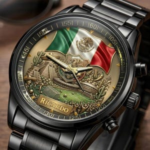 May include: Black wristwatch with a detailed face featuring the Mexican flag, a soccer stadium, and a pyramid. The watch face has gold accents and the name "RICARDO" is displayed. The watch has a black metal strap.