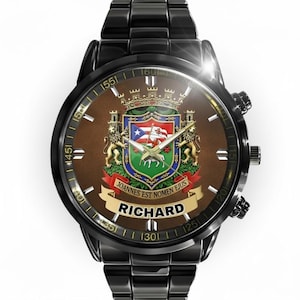 May include: Black wristwatch with a brown face featuring a coat of arms design. The watch face includes the name "RICHARD" and the phrase "JOANNES EST NOMEN EJUS". The watch has a black metal band.