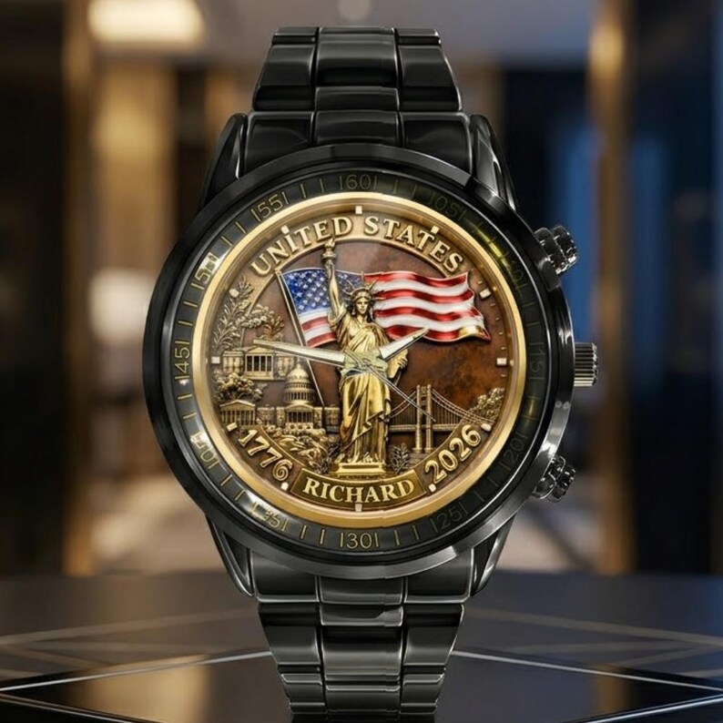 May include: Black wristwatch with a gold-toned face featuring the Statue of Liberty, an American flag, and the text "UNITED STATES 1776 RICHARD 2026". The watch has a black band and a gold-toned bezel.
