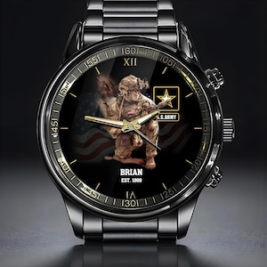 Puede incluir: Reloj de pulsera negro con una esfera detallada que presenta a un soldado del ej&eacute;rcito estadounidense arrodillado con un rifle. La esfera incluye la bandera estadounidense, el texto "U.S. ARMY" y el nombre "BRIAN" con "EST. 1988". El reloj tiene una correa de metal negro.