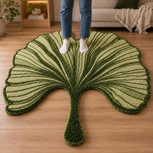Pode incluir: Um tapete de ch&atilde;o grande e texturizado em forma de folha de ginkgo. O tapete apresenta um gradiente de tons verdes, variando do s&aacute;lvia claro ao verde floresta profundo, com veios proeminentes, elevados e radiantes que imitam a folha.