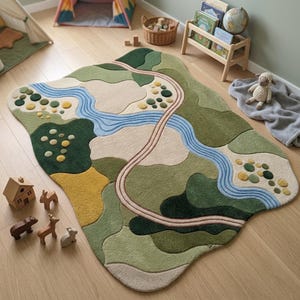 Op de afbeelding: Een vloerkleed met een landschapsontwerp in tinten groen, beige en geel. Het kleed toont een kronkelende blauwe rivier, een gebogen pad en cirkelvormige getufte accenten, wat zorgt voor een textuurrijk oppervlak met organische, vloeiende vormen.