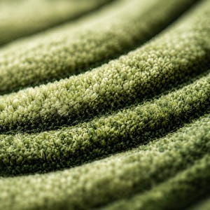 Pode incluir: Um tapete verde-s&aacute;lvia com um pelo denso e tufado, apresentando uma s&eacute;rie de cristas curvas, profundas e paralelas que criam uma textura r&iacute;tmica e ondulada na superf&iacute;cie, destacando a qualidade macia e fibrosa do material sob a luz.