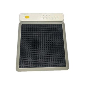 May include: A gray and black medical device with a rectangular pad covered in black, rounded protrusions. The device has a white top with a yellow button and several indicator lights. The device is designed for therapeutic use.