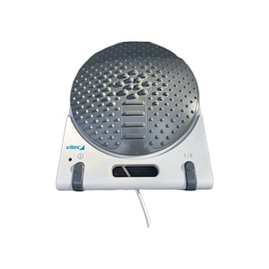 May include: A white and gray foot massager with a textured, circular top. The massager has a white base with the brand name "vitec" printed on it. The top is gray with raised bumps and a central groove. It has a power button and a small opening.
