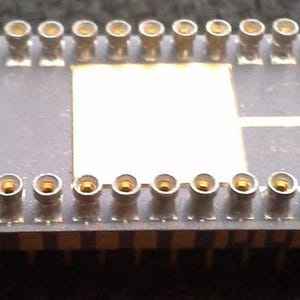 Może przedstawiać: Prostokątny, ciemnoszary element elektroniczny z dwoma rzędami złotych pinów. Element ma biały kwadratowy środek i tekst "MOSTEK 8205 38P70/02 -10 97403R PAT.PEND."