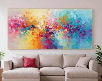 Puede incluir: Pintura de arte abstracto con marco dorado. La obra presenta una vibrante exhibición de colores, incluyendo rosa, amarillo, naranja, azul y morado. La pintura se exhibe sobre un sofá seccional beige con cojines rojos y grises.