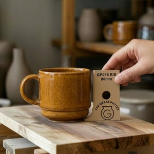 May include: A set of three ceramic mugs with a speckled, matte finish. The mugs are in shades of cream, light gray, and dark gray. Each mug has a simple, minimalist design and a rounded handle. Perfect for coffee or tea.