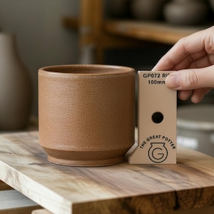 May include: A brown ceramic cylindrical planter with a textured surface. The planter has a slightly flared base and a smooth rim. A beige measuring tool with the text "GP072 R 100mm" is next to the planter.
