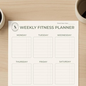 May include: A weekly fitness planner with sections for each day of the week, notes, and water intake tracking. The planner is cream-colored with a minimalist design, a coffee cup, and two pens.