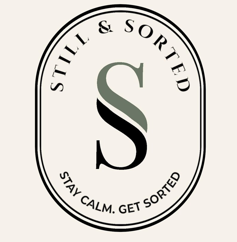 May include: An oval logo with the words "STILL & SORTED" in a circular pattern around the top. The letter "S" is the central design element, with a black and green color scheme. The text "STAY CALM. GET SORTED" is at the bottom.