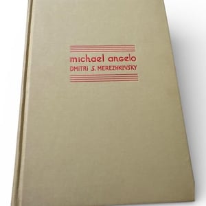 Op de afbeelding: Een hardcover boek met een beige omslag. De titel "michael angelo" en de naam van de auteur "Dmitri S. Merezhkovsky" staan in het rood op de voorkant. Het boek heeft een eenvoudig, klassiek ontwerp.