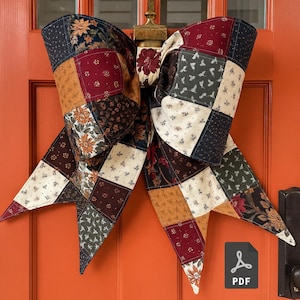 May include: A large, patchwork fabric bow in shades of burgundy, navy, tan, and cream, adorned with floral and geometric patterns. The bow is attached to an orange door, creating a rustic, country-style decoration. A PDF icon is visible.