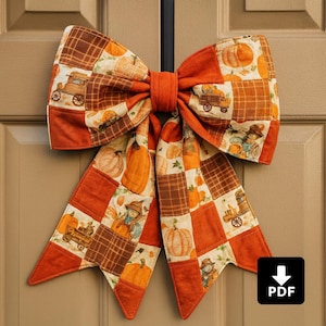 May include: A large, decorative bow made of quilted fabric, featuring a patchwork design with fall-themed patterns. The bow has a central knot and long, flowing tails. The fabric incorporates images of pumpkins, scarecrows, and harvest wagons in shades of orange, brown, and cream.