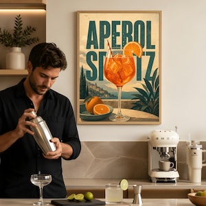 Puede incluir: Un cuadro decorativo enmarcado que muestra una ilustraci&oacute;n vibrante de un c&oacute;ctel Aperol Spritz en una copa con hielo y una rodaja de naranja, sobre un paisaje costero con el texto APEROL SPRITZ en letras grandes y llamativas.