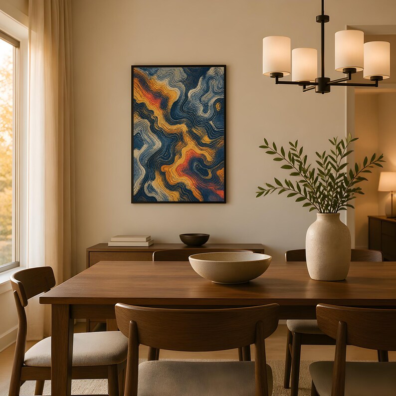 May include: A rectangular wall art piece featuring abstract swirling patterns in shades of deep blue, orange, and yellow, displayed in a black frame above a wooden dining table with a beige ceramic vase and a shallow bowl.