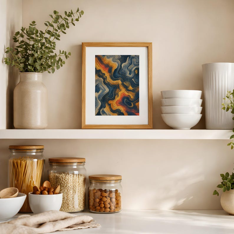 May include: A framed rectangular wall art piece featuring an abstract design of swirling, wavy lines in shades of deep navy blue, golden yellow, and burnt orange, displayed on a white shelf between a ceramic vase and a stack of white bowls.