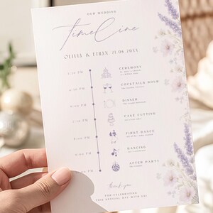 May include: A white wedding timeline card featuring purple lavender floral illustrations on the right side. The text reads: Our Wedding Timeline, Olivia & Ethan, 21 06 20XX, Ceremony, Cocktails Hour, Dinner, Cake Cutting, First Dance, Dancing, After Party.