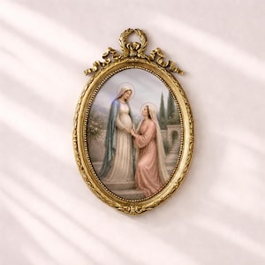 Puede incluir: Una obra de arte ovalada enmarcada en dorado. La imagen muestra a dos mujeres con t&uacute;nicas, una con una capa azul, la otra en rosa. El marco tiene una parte superior decorativa con una cinta y una corona de laurel. El fondo muestra una escena de jard&iacute;n.