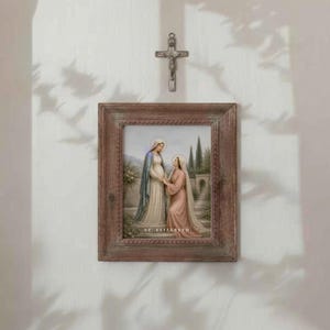 Puede incluir: Una impresi&oacute;n religiosa enmarcada que representa a dos mujeres con t&uacute;nicas, una embarazada, con halos. El marco es de color marr&oacute;n r&uacute;stico, y una peque&ntilde;a cruz de metal cuelga encima. La impresi&oacute;n est&aacute; etiquetada "ST. ELIZABETH".