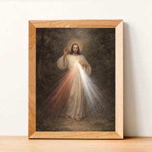 Può includere: Una stampa incorniciata di una figura religiosa, raffigurata in una veste bianca, con luce che emana dal petto. L'immagine è ambientata su uno sfondo scuro e sfocato ed è incorniciata in legno chiaro.