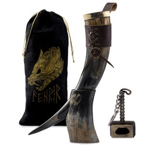 Peut inclure: Une corne à boire viking avec une sangle en cuir et une bande métallique décorative. Comprend un sac noir avec un motif de loup doré et le mot "FENRIR". Comprend également un porte-clés ouvre-bouteille en forme de marteau de Thor.