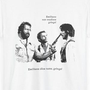 May include: White t-shirt featuring a black and white graphic of three men, one holding a gun. The text "Emiliano non tradisce gringo!" and "Emiliano dice tutto, gringo!" is printed above and below the graphic.