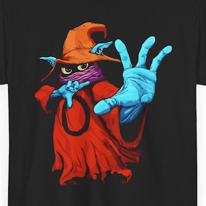 Puede incluir: Camiseta negra con una ilustración de un personaje de dibujos animados. El personaje tiene una cara morada, un sombrero naranja y una túnica roja. Las manos azules están extendidas. El diseño es una ilustración colorida.