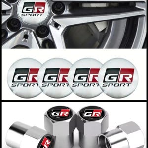 May include: Close-up of a car wheel with a silver finish and a center cap featuring the letters "GR SPORT" in black and red. The image also shows four tire valve stem caps and four round stickers with the "GR SPORT" logo.
