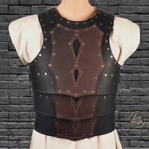 May include: A black and brown leather breastplate with rivet detailing. The breastplate has a layered design with diamond-shaped cutouts and is worn over a white garment. The overall aesthetic suggests medieval or fantasy attire.