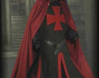 May include: A medieval costume featuring a red hooded cloak and a black tunic with a red cross emblem. The tunic has red trim and is worn with a decorative belt. The costume is set against a blurred background.