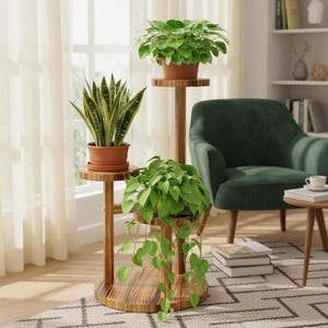 May include: Three-tiered wooden plant stand with three potted plants. The plants include a snake plant, a leafy plant, and a trailing vine plant. The stand is made of light brown wood and is in a well-lit room with a green armchair.