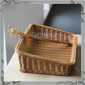 May include: A rectangular woven wicker basket in a warm brown hue. The basket features a tightly woven pattern and a sturdy construction. A bundle of dried, light brown flowers rests inside the basket, adding a touch of natural decor. The basket is suitable for storage or display.