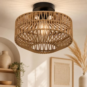 May include: A flush mount ceiling light fixture featuring a cylindrical shade crafted from woven tan rope. The fixture includes a black circular base attached to the ceiling and a single exposed light bulb centered within the woven rope structure.
