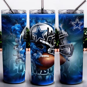 May include: A set of three stainless steel tumblers with lids and straws. Each tumbler features a blue and white design with a football helmet, a football, and the Dallas Cowboys star logo. The word "COWBOYS" is visible on one of the tumblers.